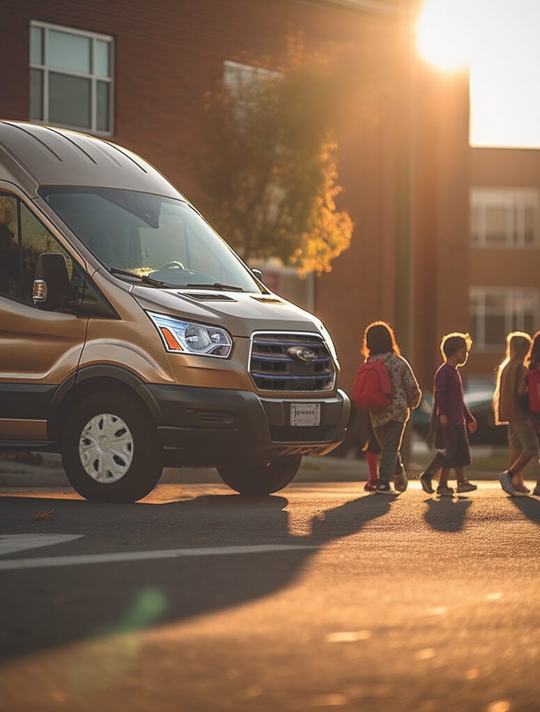 white activity bus parked in front of a school with children on the sidewalk